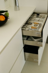 Porte ustensiles de 90cm. 19 ustensiles de marque 'Essetre' incrustés dans un support en bois blanc. Parois et fonds anti-dérapants en inox